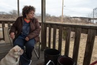 Margaret Bonnett and her dog Roxie sit on her back porch, which overlooks several acres of vacant land and construction. Bonnett has become the last resident and homeowner north of 59th Street who has no plan to sell her home to Norfolk Southern. "I've always been a quiet person, staying to myself, but maybe this is my fight—this is it," she says. "I can't see just giving up." (Photo by Max Herman)