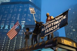 Demonstrators stand atop a bus shelter near Trump Tower to protest the presidential inauguration on Jan. 20, 2017.