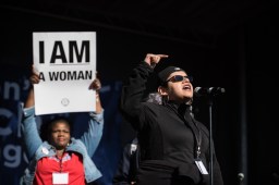 Kimberly Wasserman, executive director of the Little Village Environmental Justice Organization, speaks at the Women's March on Chicago as former aldermanic candidate Tara Stamps holds up a sign in the behind her.